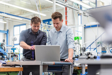 Collaboration in production hall with laptop during business meeting
