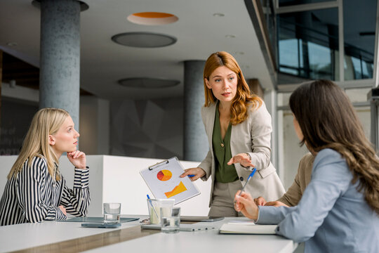 Businesswoman presenting project during meeting in modern office