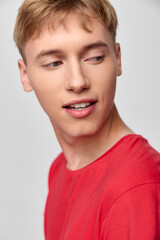 Close up of a young man in a red shirt with a sideways gaze, conveying casual confidence and everyday style for fashion, lifestyle and editorial stock photography use in marketing projects