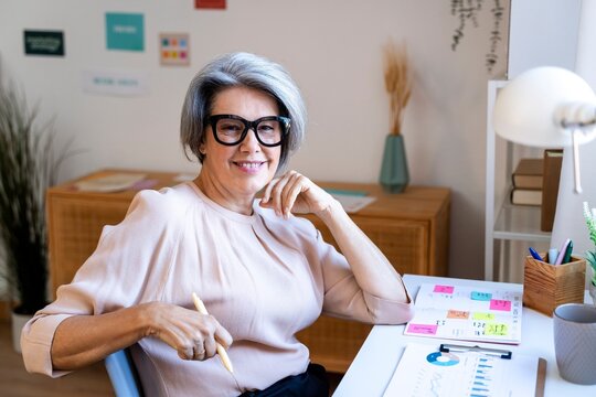 Smiling woman at desk planning and analyzing in bright modern workspace