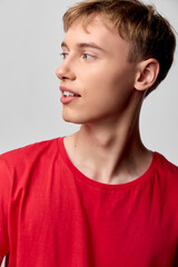 Young man wearing a red shirt in a studio setting, side view, strong lighting highlights facial profile, casual fashion vibe ideal for lifestyle and modern style photography