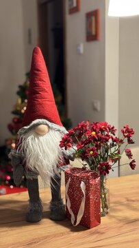 gnomo natalizio con dono ed albero di natale sullo sfondo