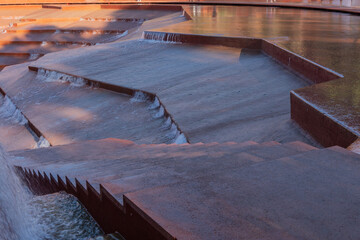 Water amphitheater or canyon in Krasnodar's city park or Galitsky Park. Architectural water feature with cascading terraces, creating a dynamic interplay of light, shadow, and flowing water.