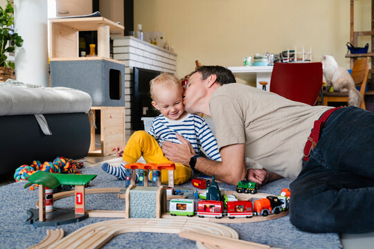 Father and son bonding while playing with toy train set at home