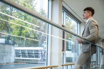 Manager in suit standing at office window looking outside