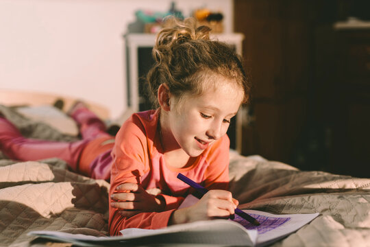 Child lying on bed drawing, creativity and focus during quality time