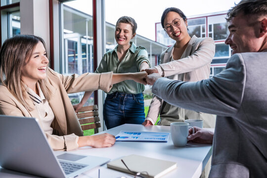 Business team celebrating success with high five in modern office