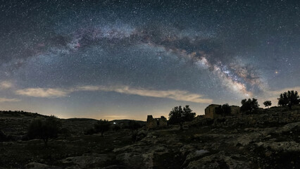 Milky Way arch over dark hills and countryside