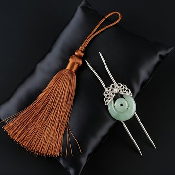 An ornate Korean Norigae silk tassel and a Binyeo (ornamental hair pin) made of jade and silver, arranged on a dark silk cushion, realistic fabric detail, black background, 