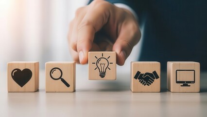 Hand placing a wooden block with a lightbulb icon among other business concept blocks