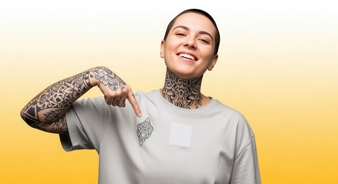 A happy tattooed woman with a buzz cut points to a design on her t-shirt. Apparel mockup for custom printing. Individuality and style concept with copy space