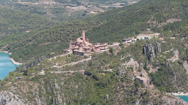 Aerial view of the Torreciudad Sanctuary, a monumental structure perched on a hilltop amidst lush greenery and turquoise waters, El Grado, Aragon, Spain.