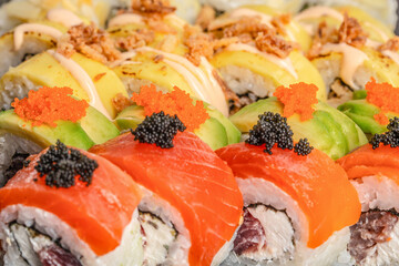 Luxury sushi rolls with salmon, avocado and red and black caviar topping in close up view