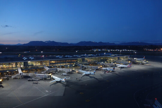 AERIAL: Fleet of passenger airplanes getting serviced at night before boarding.