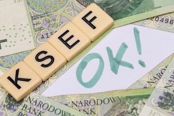 Blocks with the abbreviation OK KSEF, standing for positives about National E-invoice System, are placed against a background of loosely spread Polish 100 PLN banknotes. 