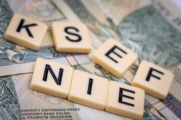 Blocks with the abbreviation KSEF NO, standing for negatives about National E-invoice System, are placed against a background of loosely spread Polish 100 PLN banknotes. 