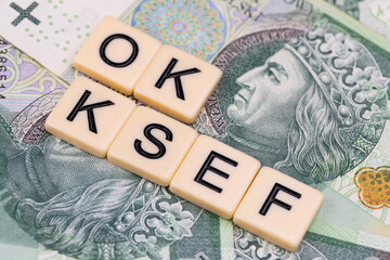 Blocks with the abbreviation OK KSEF, standing for positives about National E-invoice System, are placed against a background of loosely spread Polish 100 PLN banknotes. 