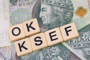 Blocks with the abbreviation OK KSEF, standing for positives about National E-invoice System, are placed against a background of loosely spread Polish 100 PLN banknotes. 
