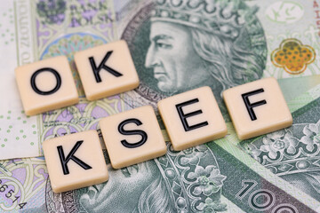 Blocks with the abbreviation OK KSEF, standing for positives about National E-invoice System, are placed against a background of loosely spread Polish 100 PLN banknotes. 