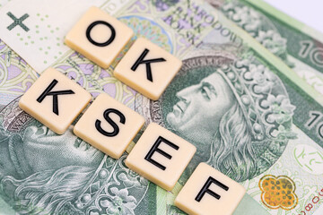 Blocks with the abbreviation OK KSEF, standing for positives about National E-invoice System, are placed against a background of loosely spread Polish 100 PLN banknotes. 
