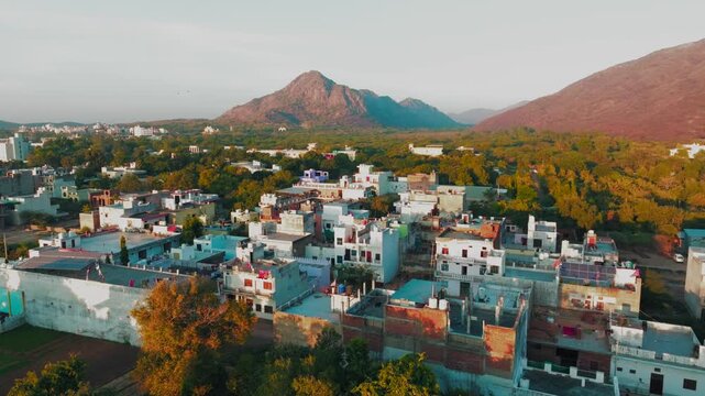 Aerial view of houses and trees, with a mountain in the background, showcasing the landscape's natural beauty and urban integration, Pushkar, Rajasthan, India.