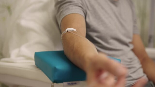 Male patient receiving intravenous infusion treatment through iv drip on their arm, focusing on healthcare, medicine, medical therapy, and vitamin benefits in clinic. Concept of healthy lifestyle.