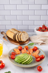 Artisan bread, cherry tomatoes and avocado with salmon plate on bright white background. Fresh and healthy ingredients. Concept of balanced diet and nutritious breakfast