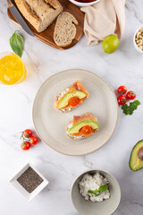 Top view of healthy breakfast with avocado and salmon toasts, whole grain bread, ricotta, kombucha and nuts. Concept of clean eating and natural lifestyle