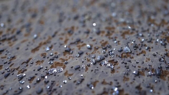 Closeup of mineral textured surface, Macro image showcasing mineral fragments and luminous accents, Close examination revealing coarse mineral particles and shimmering highlights in subdued hues