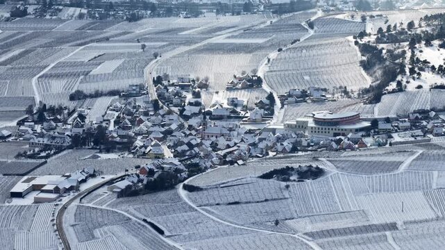 Aerial view of Orschwiller blanketed in stark white snow, contrasting against the dark linear patterns of the vineyards, Orschwiller, Grand Est, France.