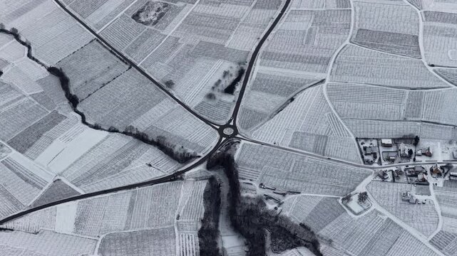 Aerial view of the snow-covered vineyards, roads, and a small village create a stark contrast in the winter landscape, Orschwiller, Grand Est, France.