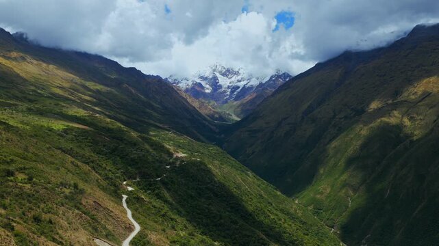 Windy dirt road Soray Mount Humantay Salkantay trek Peru aerial drone Peruvian Andes high altitude snow capped glacier peaks Laguna Humantay Lake rainy season morning sunny cloudy forward motion