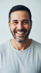 Obraz premium Smiling Man with Dark Hair and Stubble Wearing Light Blue T-Shirt Isolated on Light Gray