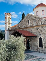 Panagia Eleousa Church (&Pi;&alpha;&nu;&alpha;&gamma;ί&alpha; &Epsilon;&lambda;&epsilon;&omicron;ύ&sigma;&alpha;) in Agros village, Cyprus, featuring stone walls, red-tiled roof, surrounded by green mountain slopes and traditional village scenery