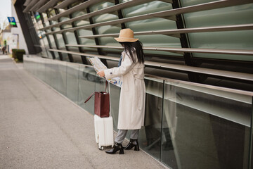 Woman Traveler Reading Map Beside Modern Glass Building