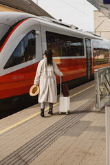 Traveler with suitcase boarding modern red train