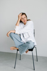 Stylish Woman Sitting On Chair In Studio