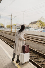 Woman with suitcase waiting on train platform