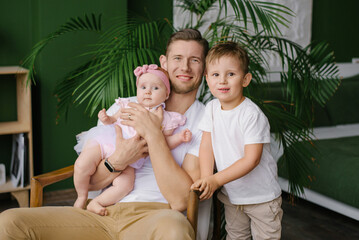 Father Hugging Baby Daughter With Son Nearby