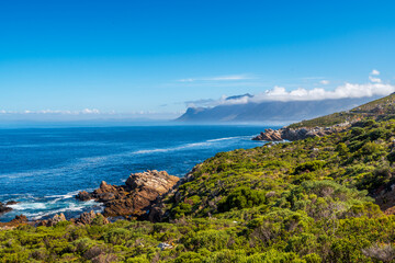 Naklejka premium Holiday views of cloud-covered Hottentots Holland Mountains from Clarence Drive, between Gordon's Bay and Rooi-Els, Western Cape, South Africa. Perfect scenic drive for road trips and travel.