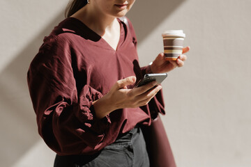 Woman Using Smartphone While Holding Takeaway Coffee