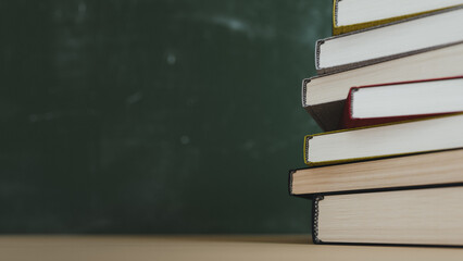 Stack of Hardcover Books on Desk with Green Blackboard Copy space. 3d rendering