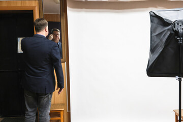 Man Combing Hair Front of Mirror at Professional Photo Studio.