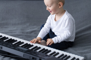 Happy little child trying to play piano. Child happy to heart sounds of piano.