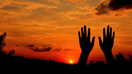 Silhouettes of outstretched hands against a vibrant sunset.