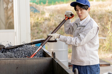 金属の廃材を片付ける男性作業員　