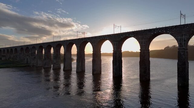 Aerial view of the Royal Border Bridge spanning the river, its stone arches casting long shadows in the setting sun, Berwick-upon-Tweed, England, United Kingdom.