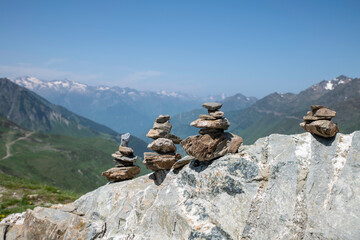 Stacked Stone Cairns On Rocky Ridge With Mountain Range And Clear Blue Sky