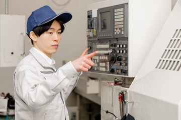 工場の操作盤の前で働く男性作業員