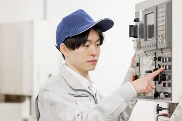 工場の操作盤の前で働く男性作業員